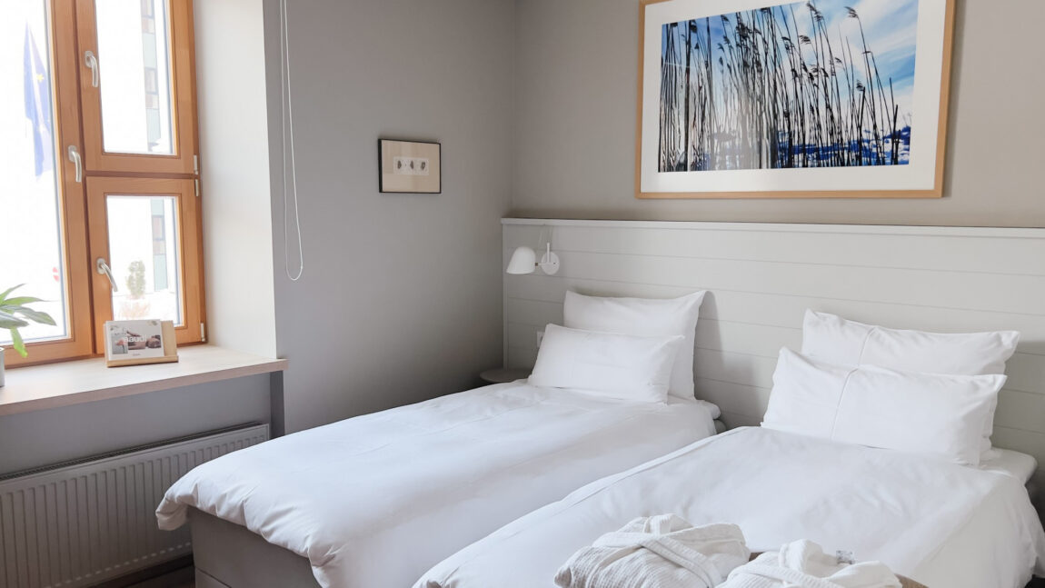 LaSpa beach house twin room with two single beds, soft natural light, minimalist Nordic interior and wooden window details